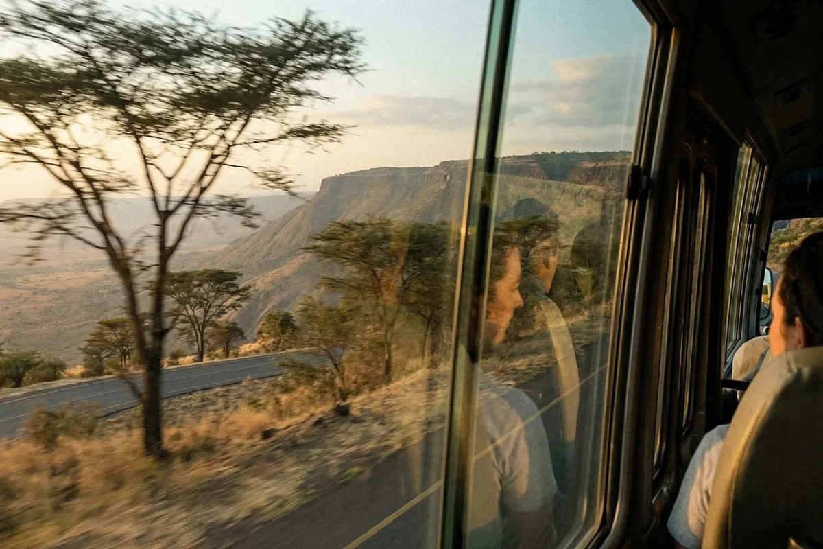 View from the shuttle bus window of acacia trees and the Rift Valley escarpment on the way to Arusha